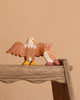 Two figures from the Holztiger Handmade Wooden Woodland Animals Set—an eagle with outstretched wings and an owl, crafted from maple and beech wood—are displayed side by side on a rustic wooden surface against a beige background.