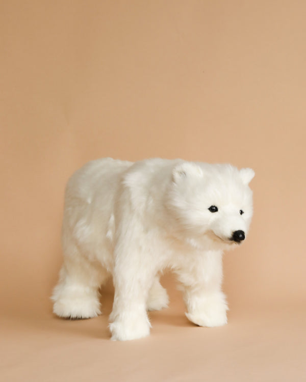 A hand-sewn Polar Bear Cub Stuffed Animal on a soft beige background, looking to the left with a gentle expression.