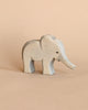 A Small Ostheimer Elephant - Trunk Out figurine with a smooth finish and painted black eyes, standing against a plain beige background.