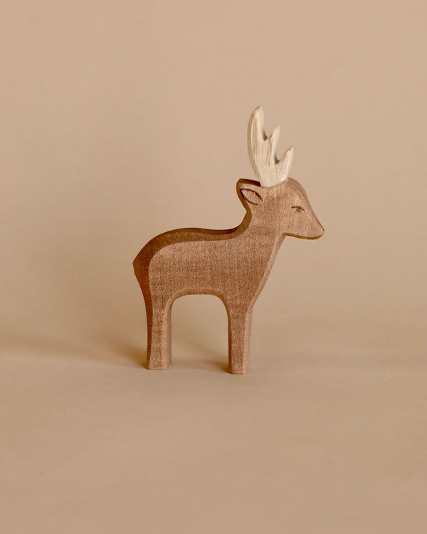 A Ostheimer Deer with prominent antlers, standing against a plain beige background. The figure displays a smooth texture and simplistic design typical of Ostheimer toys.