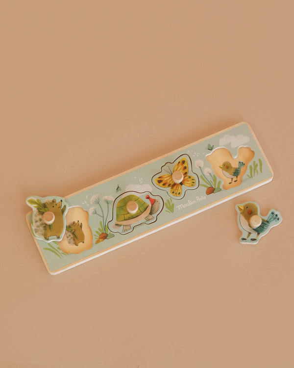The Moulin Roty Wooden Animal Puzzle - The Three Little Rabbits features four charming animal pieces—a hedgehog, turtle, butterfly, and bird—set against a beige background, ideal as a toddler shape sorter.