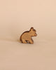 The Ostheimer Handmade Wooden Bear Set features a small, brown, handcrafted wooden bear figurine displayed on a beige surface and background.