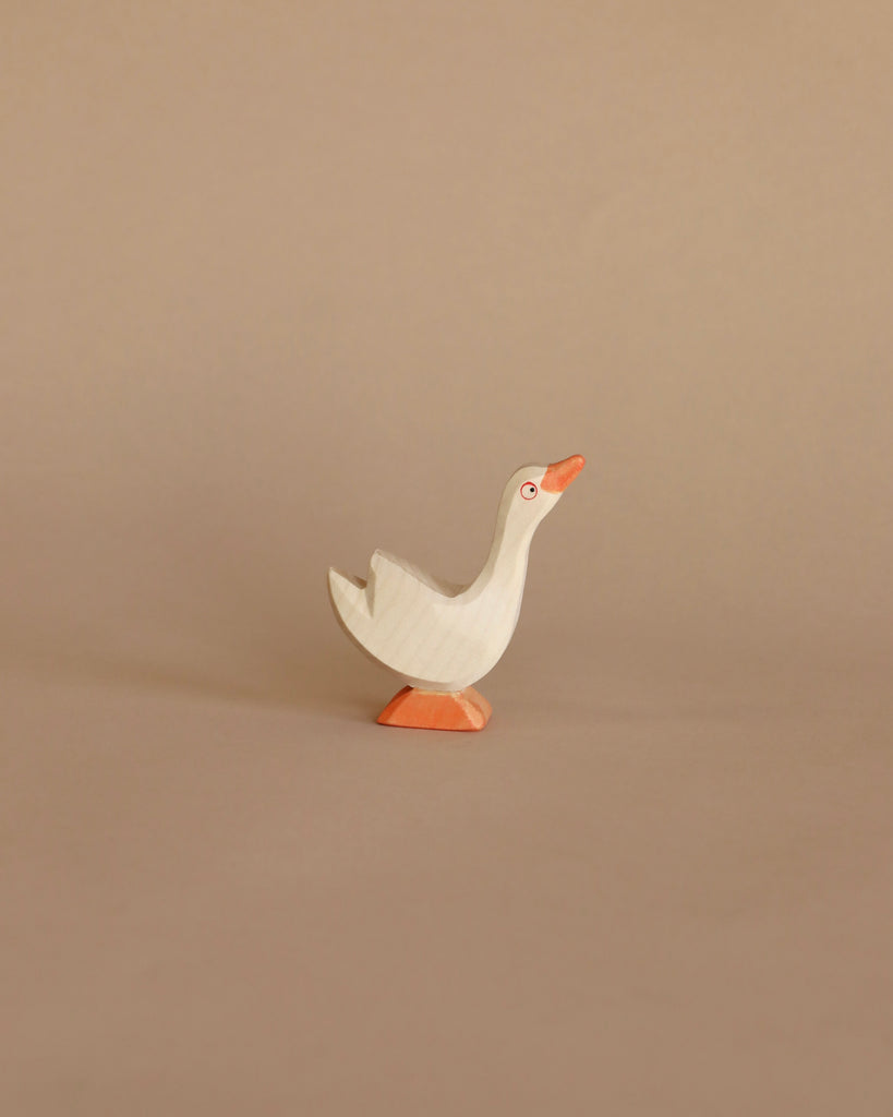 A simple handcrafted Ostheimer Goose - Head Up toy with a white body and orange beak and feet, standing against a plain beige background.