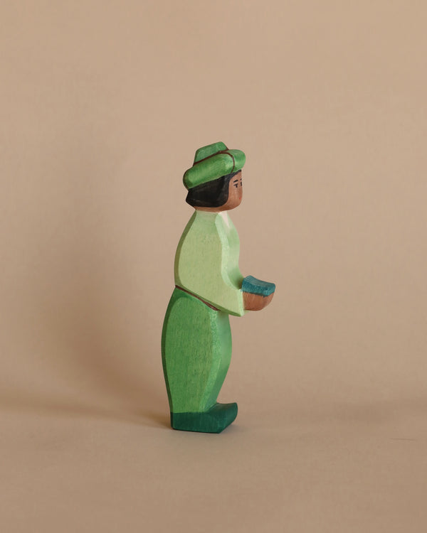 A handcrafted Ostheimer Green King figurine, depicted in a side profile, set against a plain light brown background.