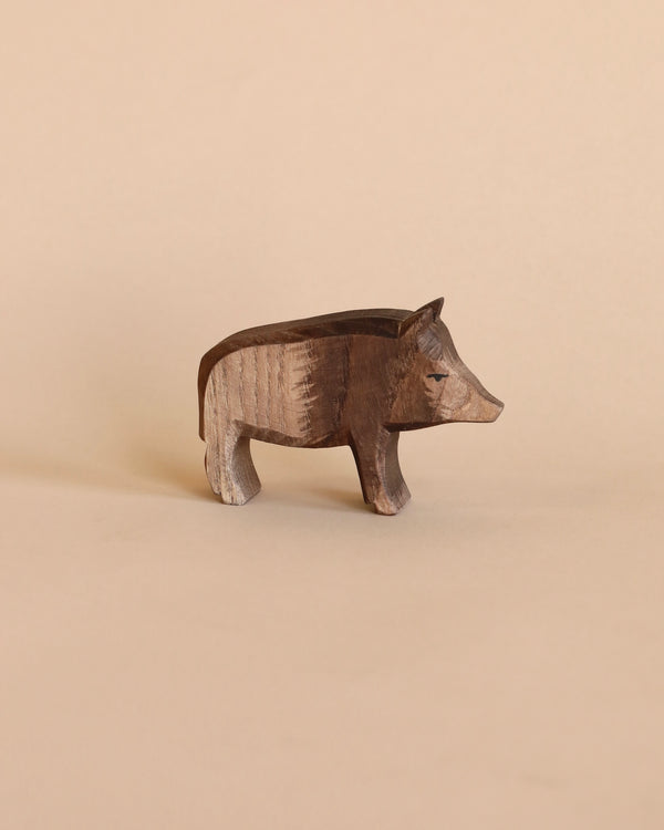 A handcrafted Ostheimer Wild Boar figurine, displayed against a soft beige background, featuring detailed textures and a lifelike pose.