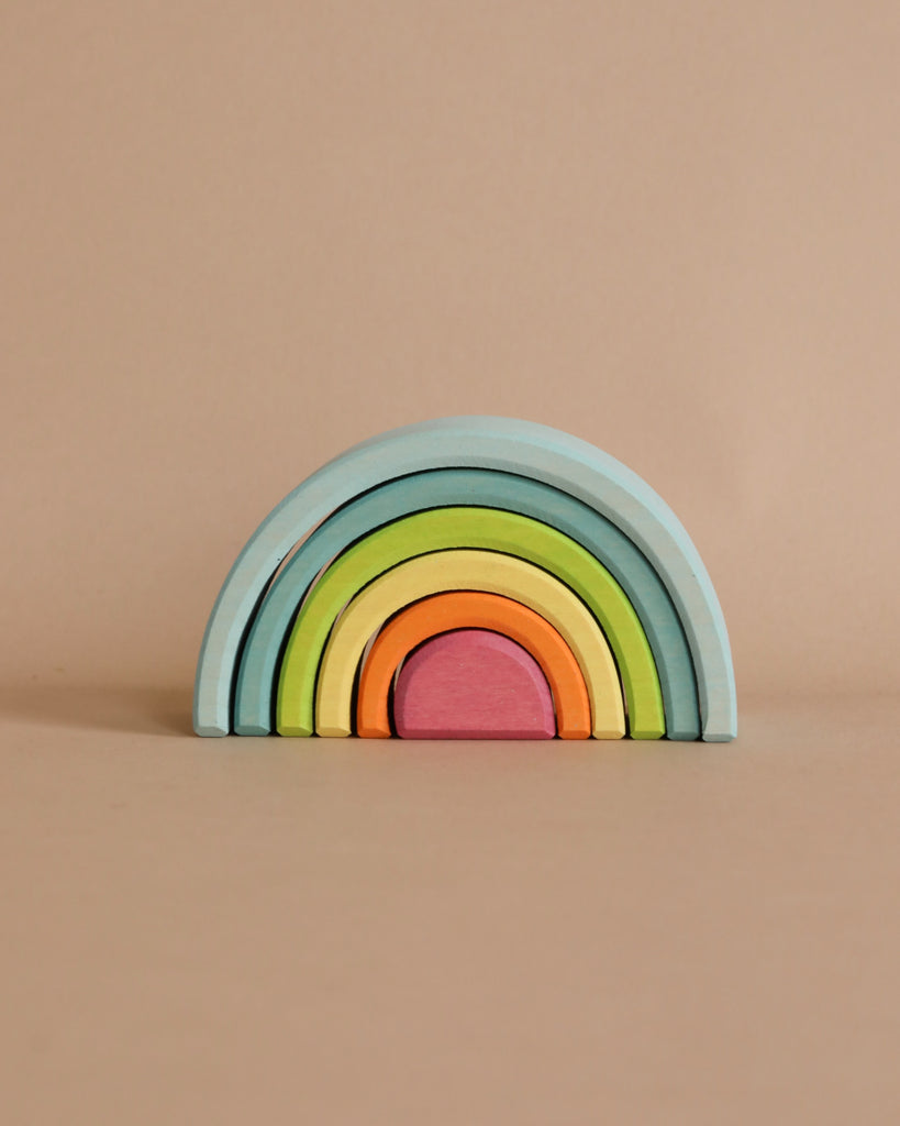 A minimalist photo of a Newborn Gift Set - Blue with pastel-colored items arranged together, set against a plain beige background.