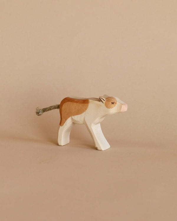 A handcrafted Ostheimer Calf - Drinking with a natural finish and painted details in white and tan, standing against a plain light beige background.