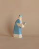 A handcrafted Ostheimer Blue King With Crown wooden figurine painted to resemble a person wearing a blue and white outfit, depicted in a praying or contemplative pose, against a plain beige background.