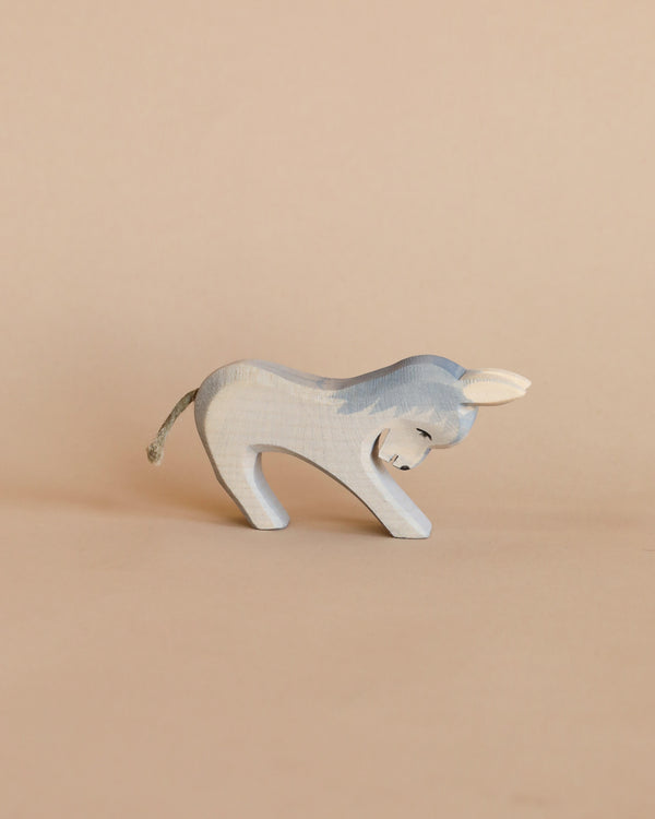 A handcrafted Ostheimer Donkey - Stubborn, painted light blue with visible wood grain, posed against a plain beige background. The donkey has small white ears and a thin tail.