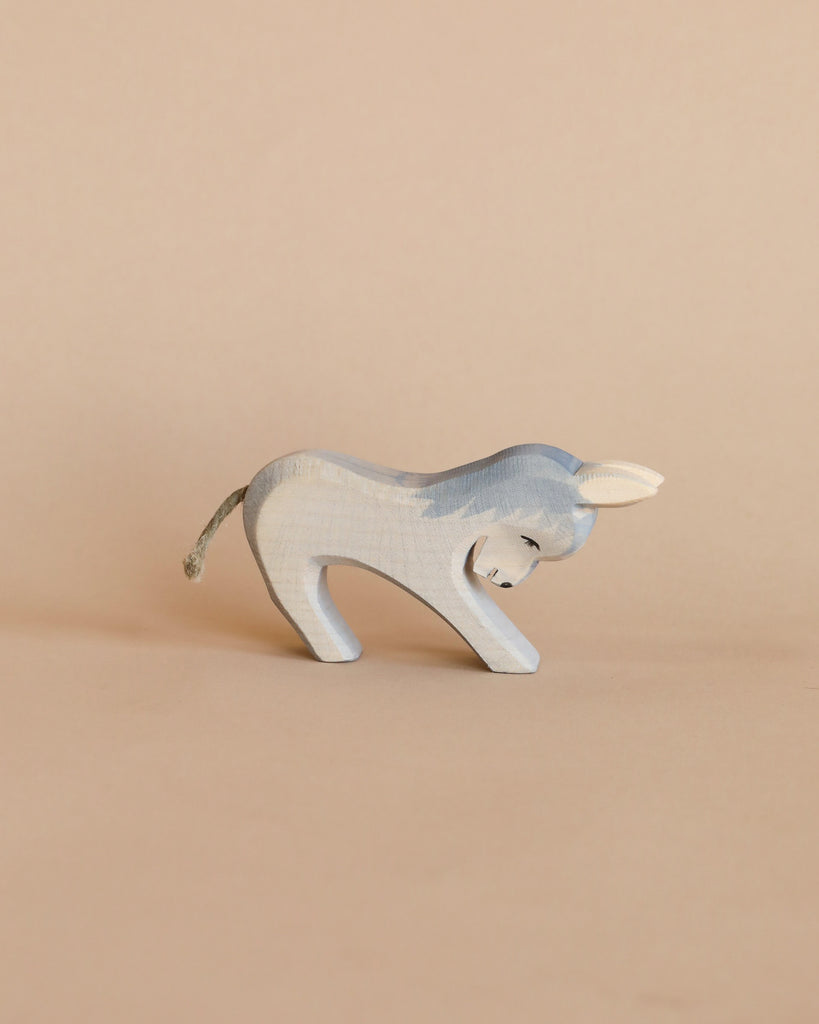A handcrafted Ostheimer Donkey - Stubborn, painted light blue with visible wood grain, posed against a plain beige background. The donkey has small white ears and a thin tail.