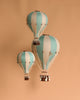 The Hot Air Balloon - Pastel Green features teal and white stripes with a small wicker basket attached by white strings, creating a charming handmade decoration ideal for a child's room.
