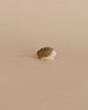A small carved wooden hedgehog from the Enchanted Woodland Farm Set, featuring a brown back and white face inspired by Ostheimer toys, is displayed on a light beige background.