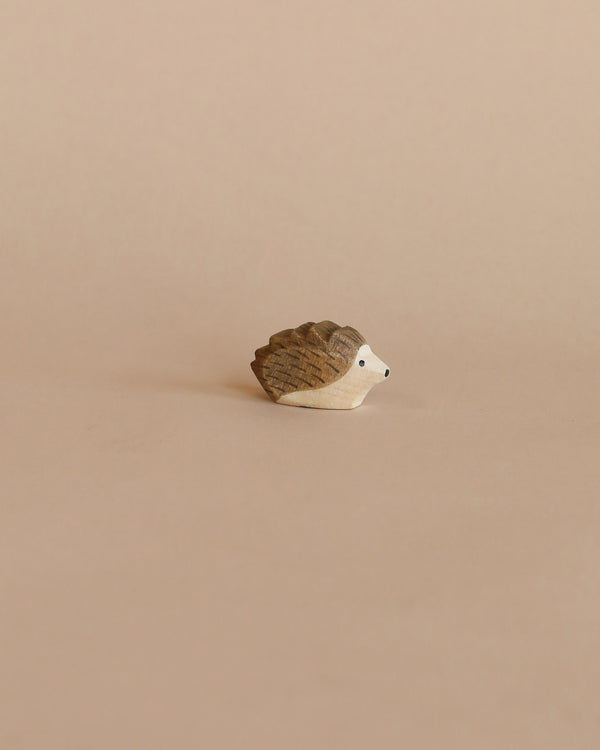 A handcrafted Ostheimer Hedgehog - Small, characterized by a simple yet precise design, on a smooth beige background. The hedgehog is small, with visible wood grain and a cute, painted.