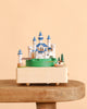 Forest Castle Music Box featuring a miniature castle on a green hill with a small boat and bridge.