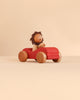A Sabo Concept Car with Lion featuring a wooden lion driving a red wooden toy car.