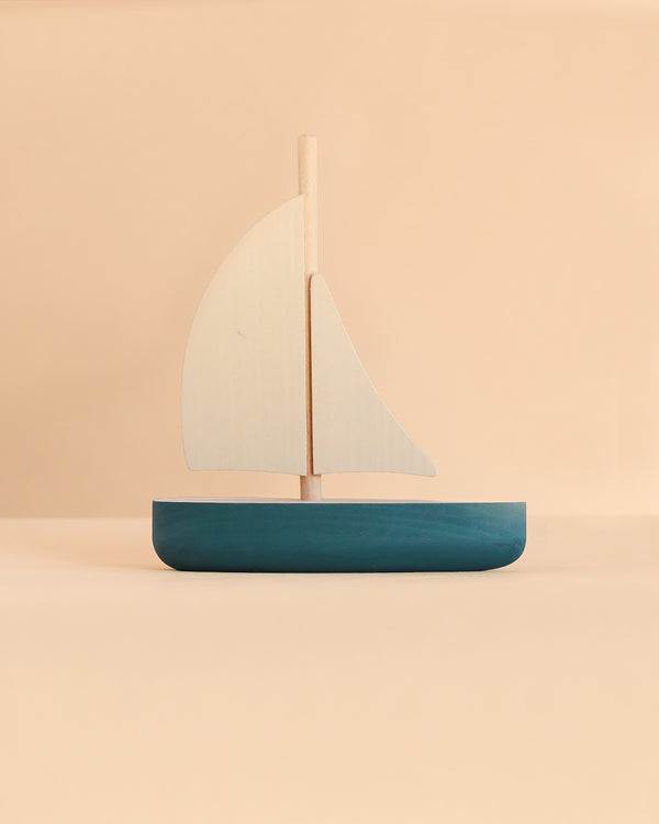 A Sabo Concept Sailboat, a minimalist wooden toy with a dark blue hull and two light-colored sails, perfect for imaginative play.