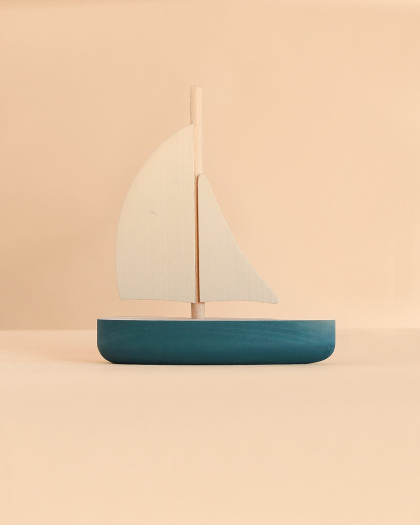 A Sabo Concept Sailboat, a minimalist wooden toy with a dark blue hull and two light-colored sails, perfect for imaginative play.