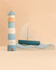 Sabo Concept Sea Adventure Set featuring a wooden blue and white striped lighthouse and a sailboat sitting on two wavy, block-style ocean waves.