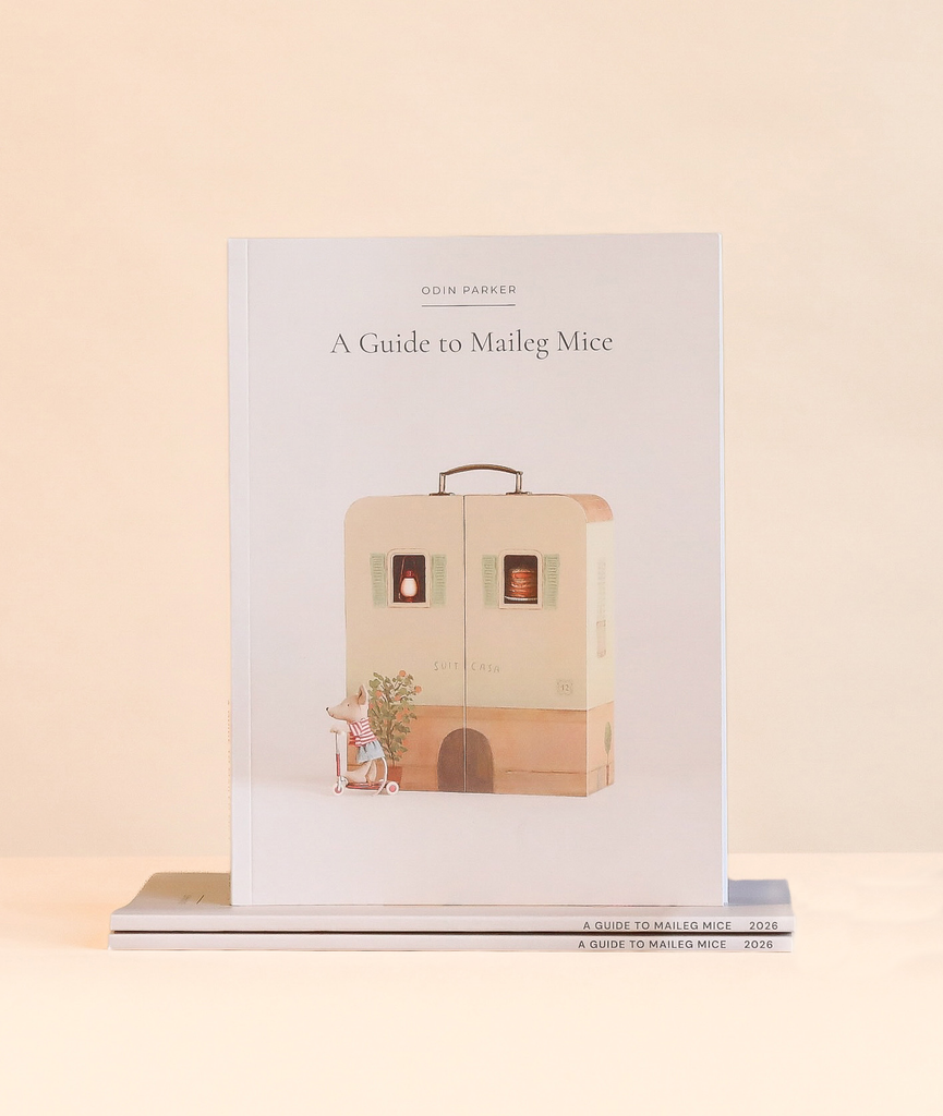 Odin Parker’s Maileg Catalog featuring an illustration of a toy mouse on a scooter in front of a suitcase house in this miniature world.