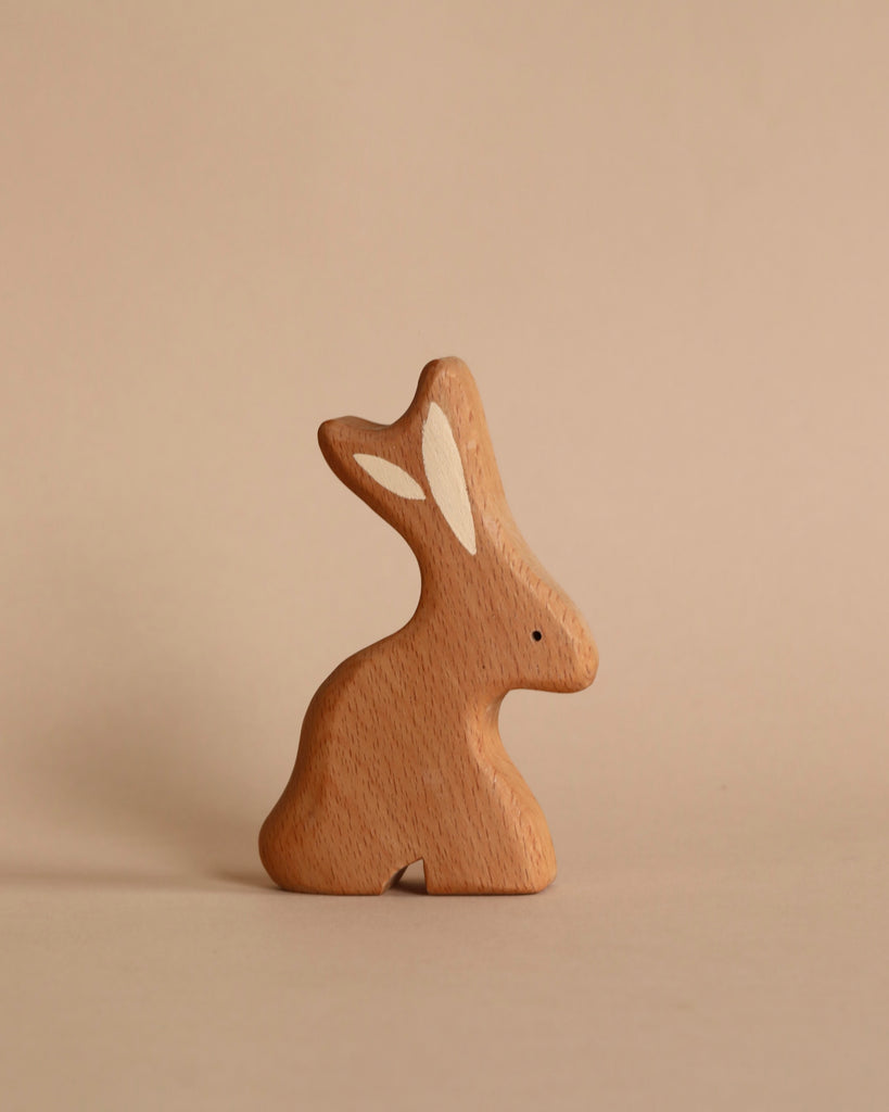 A Handmade Wooden Bunny figurine from Tevi Toys, elegantly carved with a heart-shaped cutout on its back, stands against a plain beige background.