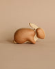 A Handmade Wooden Bunny with a smooth finish, featuring a distinctive rounded body and long ears, handcrafted from sustainably harvested hardwood, set against a soft beige background.