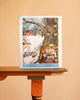 The Cold Hollow - 1000 Piece Jigsaw Puzzle box features an owl perched on a snowy tree, with animals having tea inside a hollow trunk and a red cabin in the background.