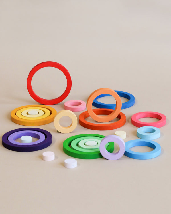 Colorful Grapat Nesting Rings in various sizes and colors, including red, blue, green, and yellow, arranged asymmetrically on a beige background.