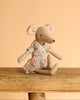 The Maileg Mum Mouse, elegantly dressed in a charming patterned outfit, is poised gracefully on a wooden surface alongside delightful toy accessories against a neutral backdrop.