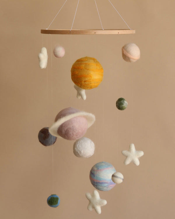 A Handmade Mobile - Outer Space - Final Sale featuring felty textured spheres representing planets and stars, suspended from a wooden frame against a neutral background. The colors vary, with a prominent yellow-orange sphere resembling the sun.