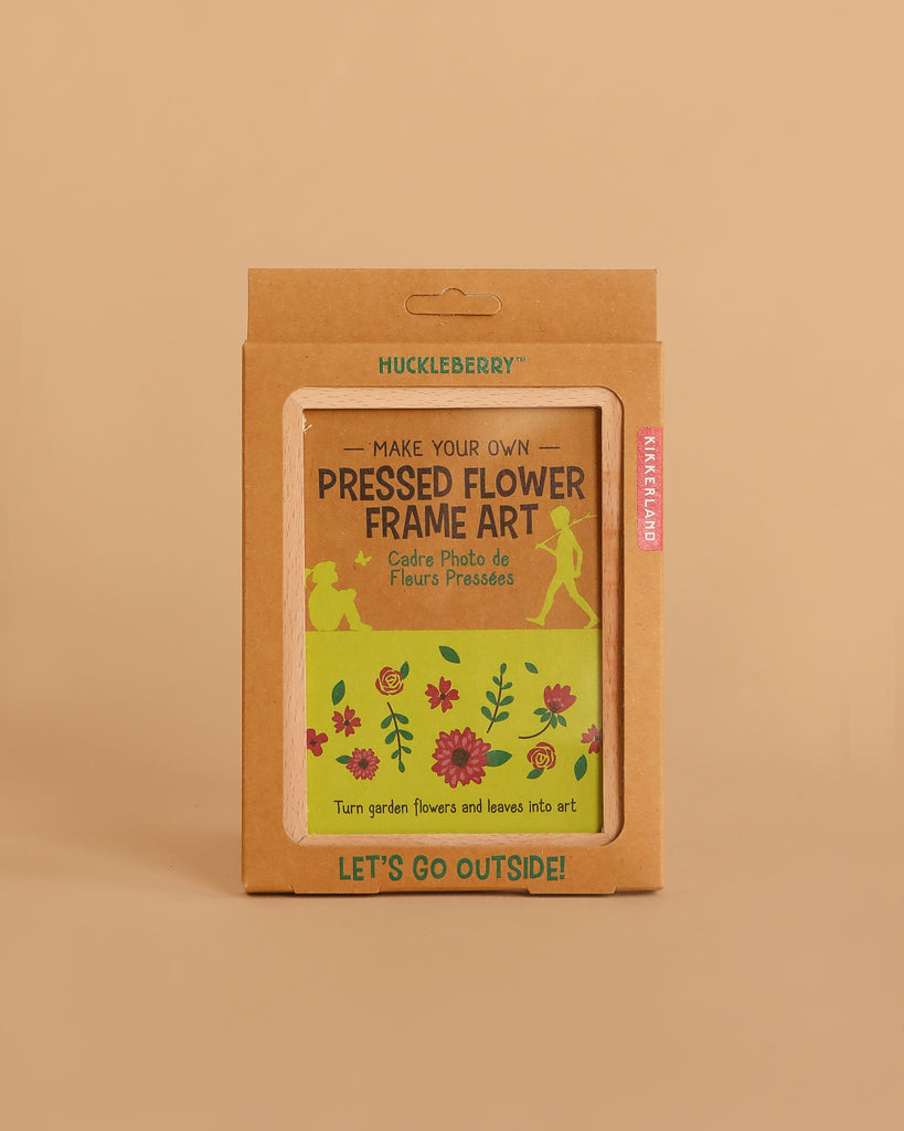 The Huckleberry Pressed Flower Frame kit, in green and brown packaging with floral and nature-themed illustrations, includes a beechwood frame and is displayed on a plain beige background.
