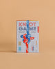 The Knot Game boxed set, shown on a tan background with a colorful knotted rope, teaches over 20 knot-tying skills. Includes game pieces and is designed for ages 8 and up.