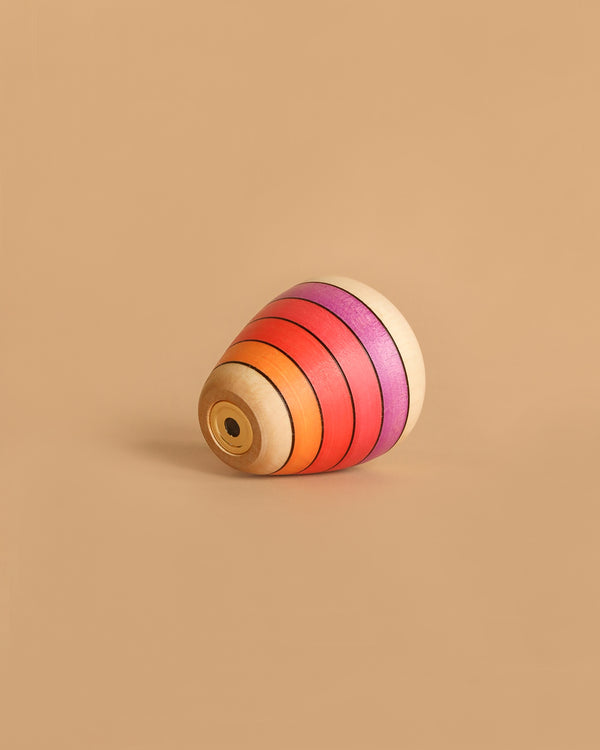 The Mader Wooden Kaleidoscope - Pink is a classic wooden spinning top with colorful pink-themed rings, set against a plain beige background.