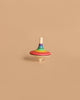 The Mader Rallye Rainbow Spinning Top, Small - Red features vibrant concentric stripes and stands upright on a beige background, making it a delightful toy for 3-year-olds.