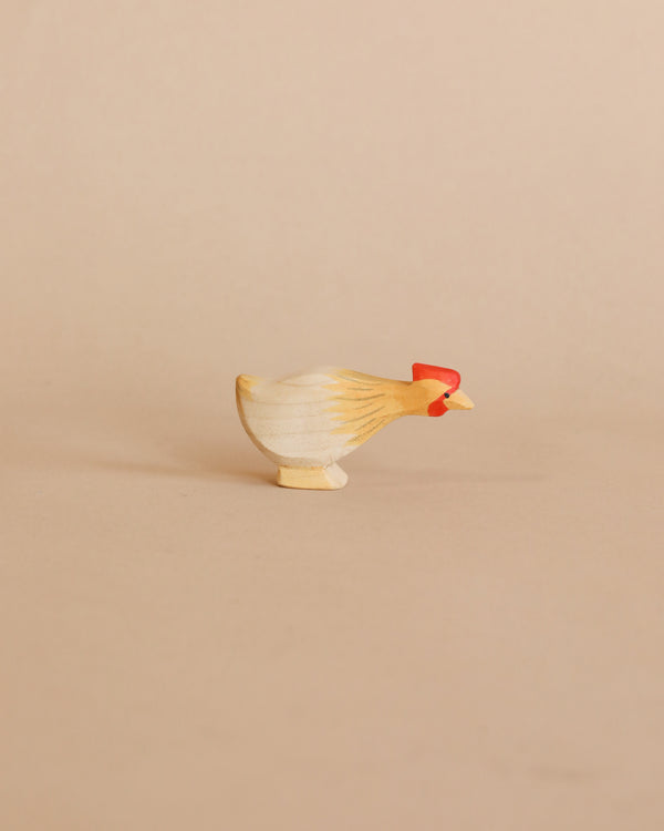 A small, hand-carved Ostheimer Long Neck Hen - Ochre figurine with a natural wood finish and painted red details on a plain beige background, perfect for imaginative play.