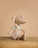 The Maileg Mom and Dad Living Room Set features a fabric mouse doll in a patterned dress seated by a charming tea set on a wooden surface, all set against a plain beige background.
