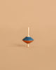 The Mader Tukanino Spinning Top - Blue features a maple wood top with blue and orange stripes, standing upright on a beige background and recalling the charm of classic Austrian toys.