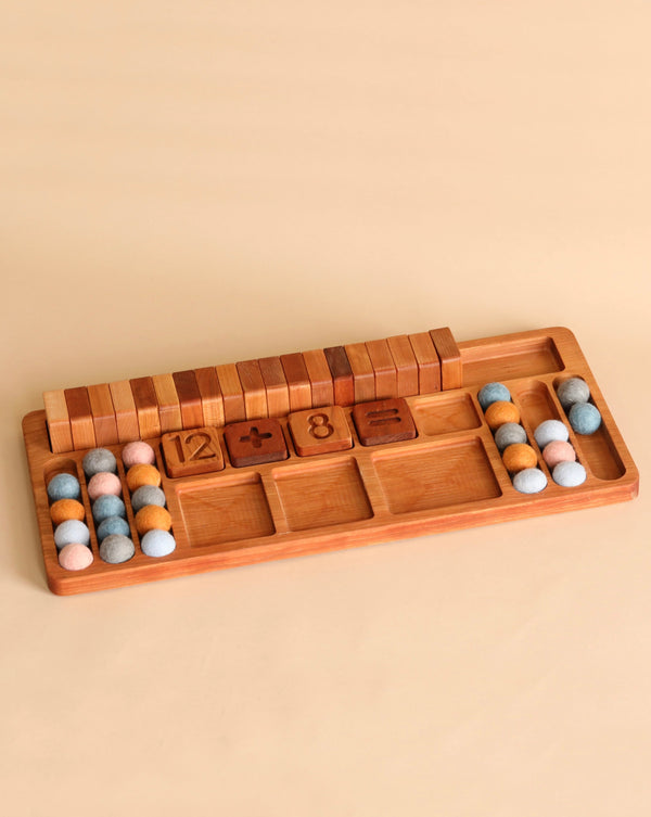 A wooden educational math board, The Original Extended Math Board - Made in USA, featuring carved slots with numbers and mathematical symbols, accompanied by colorful felt balls for counting, arranged on a beige background.