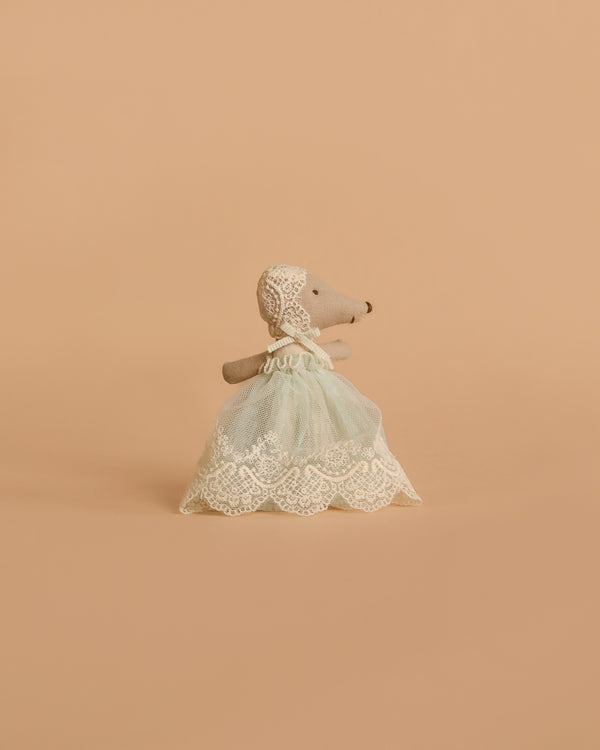The Maileg Baby Mouse in Gown - Mint stands upright, dressed in a mint celebration gown and lace bonnet, against a plain beige background.