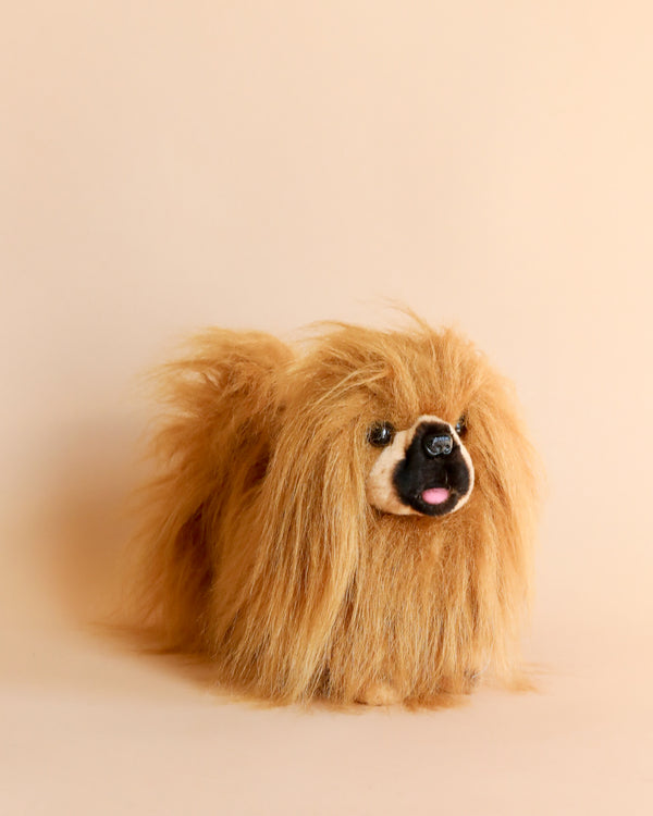 A fluffy, long-haired Pekingese Dog Stuffed Animal with realistic features and a joyful expression posing against a soft peach background.