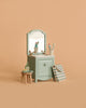 The Maileg Bathroom Set features a mint green sink dresser with mirror, two toothbrushes in a cup, toothpaste, soap, striped bag, and brush on a table and stool—all displayed against a plain beige background.