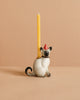 The Siamese Cat Cake Topper features a ceramic cat wearing a red party hat and holding a yellow taper candle on its back, ideal for cat-themed celebrations. The topper is displayed against a plain beige background.