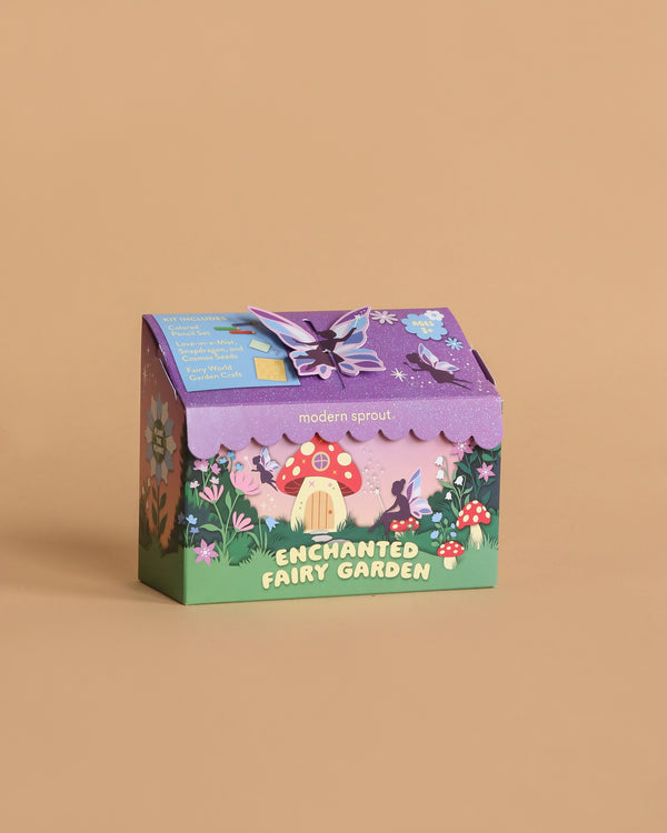 The Magical Minds Garden Kit - Enchanted Fairy Garden comes in a colorful box with whimsical illustrations of a fairy house, mushrooms, flowers, and a purple butterfly on tan—an ideal STEM DIY activity for kids.