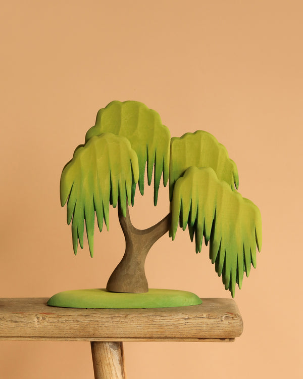 The Bumbu Handmade Wooden Large Willow Tree features stylized green leaves on a small green mound, ideal as nature-inspired decor for any space.