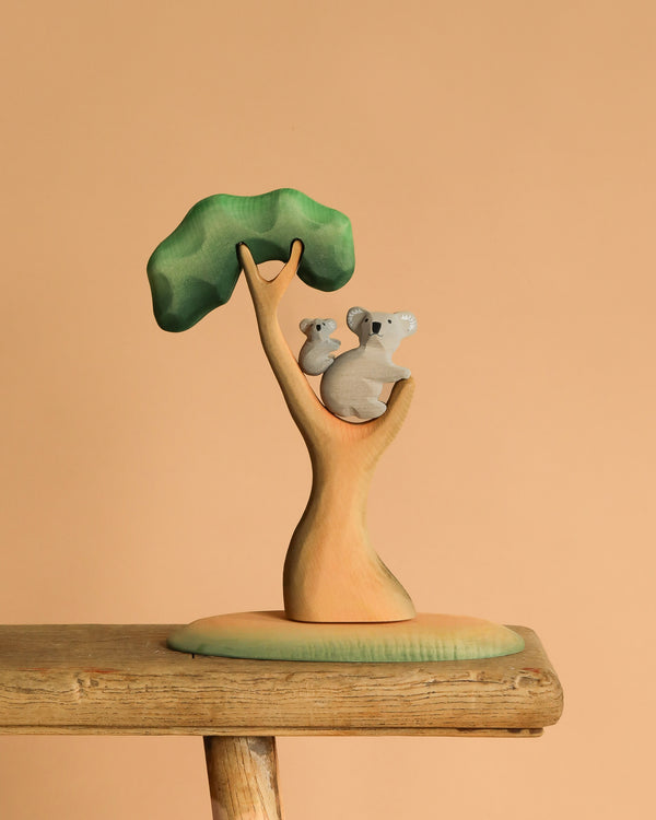 The Bumbu Handmade Wooden Koala Bears with Eucalyptus Tree Set features two eco-friendly koalas in a stylized tree, perfect as a handmade toy or decorative piece for any room.