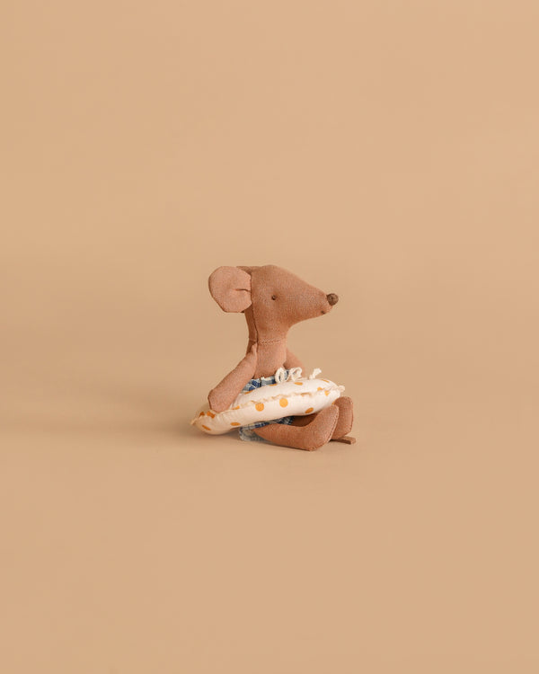 The Maileg Beach Mouse with Float, Little Brother - Yellow Dots sits against a beige background, holding a yellow polka-dotted swim ring and wearing blue swim trunks.