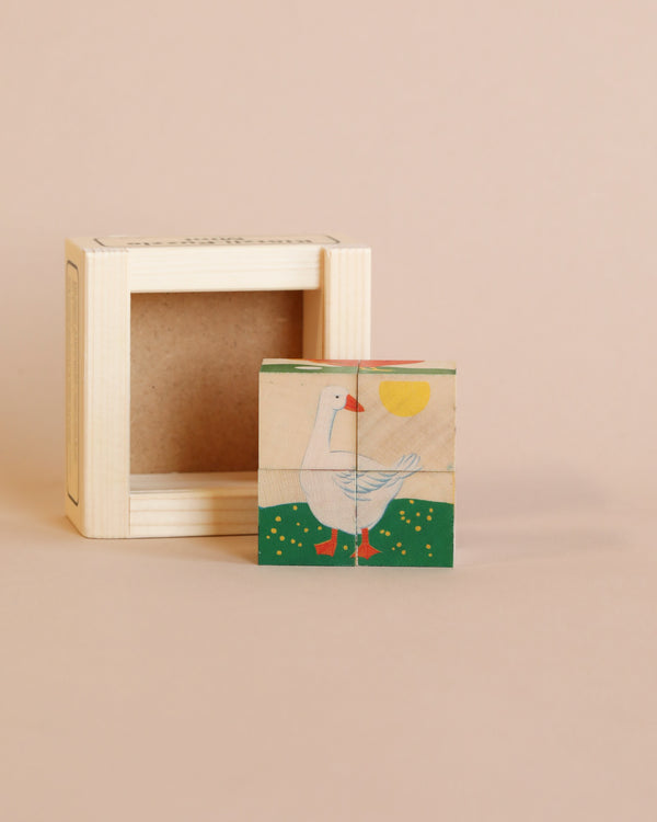A small Wooden Block Puzzle - Mini 4 Piece Domestic Animals with a printed image of a white bird standing on one leg, placed in front of an empty wooden frame, against a soft pink background.
