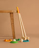 Two wooden mallets with colored handles from the Mini Golf Set lean against a table, beside three balls and colorful golf pieces—an ideal set for introducing kids to backyard mini golf fun.
