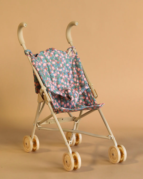 The Konges Sloejd Doll Stroller - Kyoto features a lightweight white metal frame, wooden wheels, and a fabric seat in a blue and pink floral pattern on a beige background.
