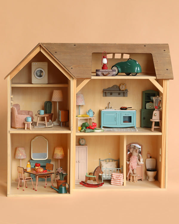 The Maileg Fully Furnished Farmhouse Set + Surprise Gift (ships in 1-2 weeks) features a charming wooden farmhouse with six rooms, complete with vintage-inspired Maileg miniature furniture and delightful accessories throughout.