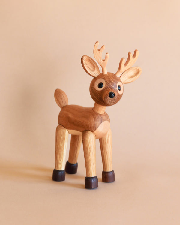 A Spring Copenhagen Spirit The Deer figurine with large eyes and antlers stands against a plain, light beige background. Its legs and hooves show distinct brown and black coloring.